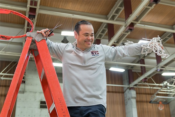 coach danny cutting rope of basketball hoop