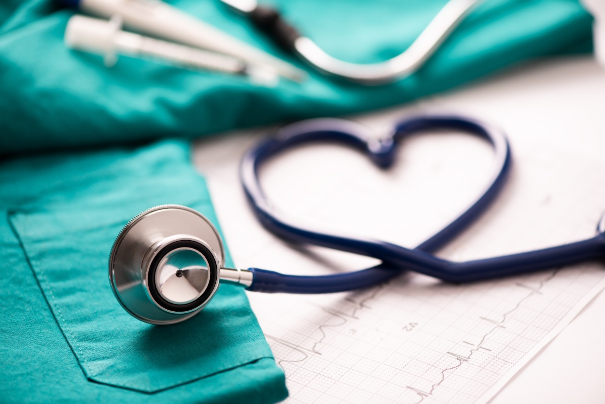 image of a stethoscope forming a heart on top of scrubs and heart monitor signals