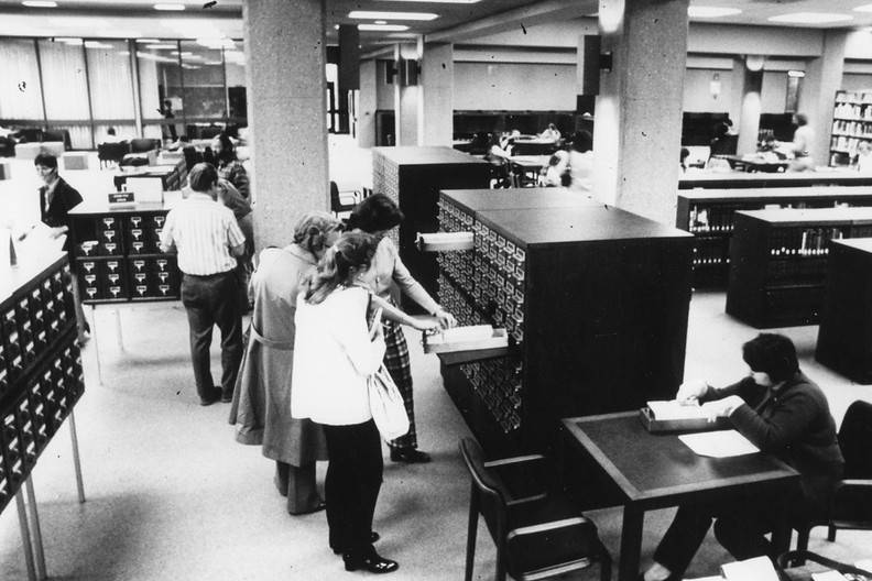 black and white photo with patrons looking through archival boxes