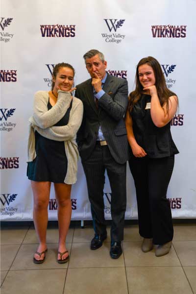 Brad posing with students in front of step and repeat