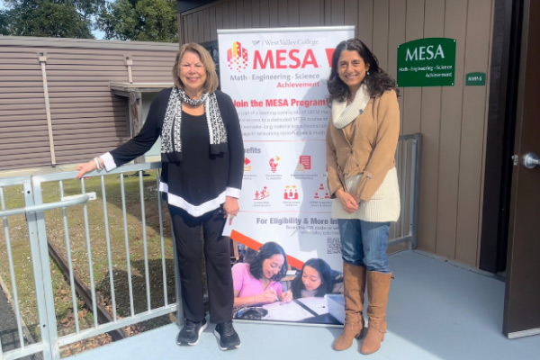 Two people standing in front of a MESA banner.