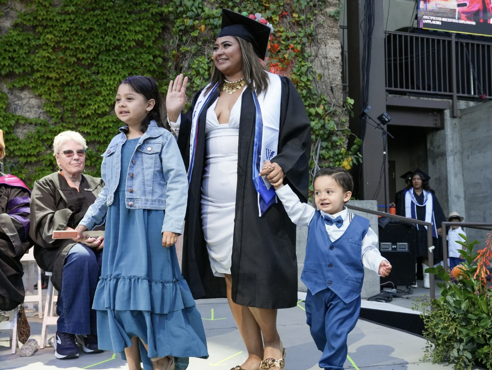 student parent with their kid walking stage at commencement